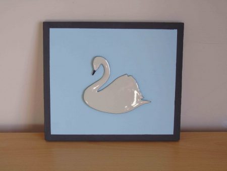 White enamelled swan on blue wooden board
