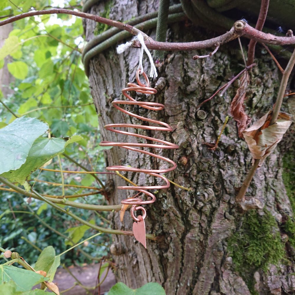 Spiral copper garden decoration hanging from a tree