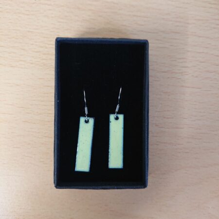 Pale green rectangular enamelled earrings in their presentation box. The earrings have surgical steel earhooks. The green was overfired to give dark tiny dots