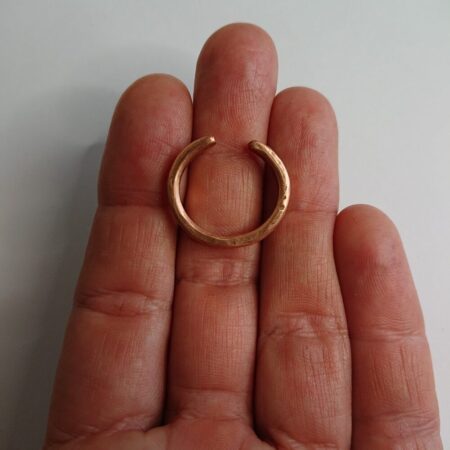 Chunky copper wire ring being held. The ring is shiny copper with hammer marks. This is the thicker version I make