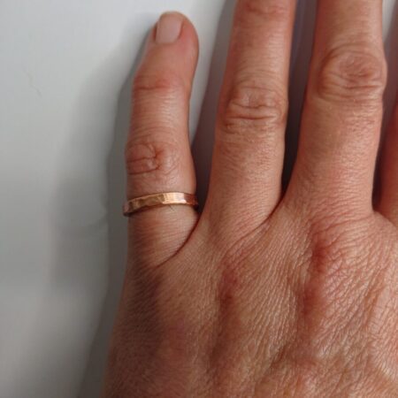Chunky wire copper cuff ring. It is a flattened round band with small gap. The ring has light hammer marks and is in bright, shiny, fresh copper. This is the slightly thinner version. This picture shows the ring being worn.