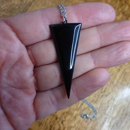 Black enamelled copper necklace on a silver coloured chain. The pendant is an elongated triangle with the flat edge across the top (a drop triangle)