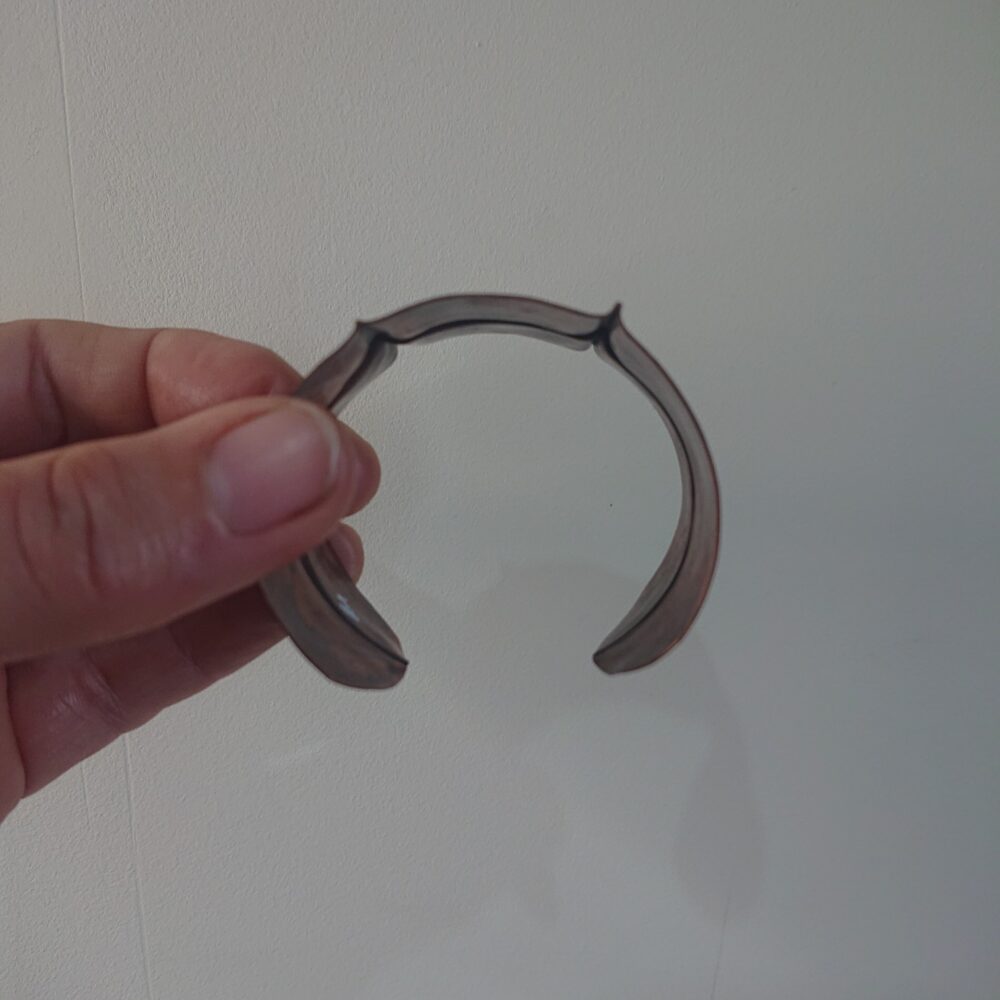 Copper bracelet with fold-formed ridges in a chunky cuff style. There is a centre ridge line, plus two vertical ridge or fold lines. It has an aged copper colour patina, so a mid to darker brown