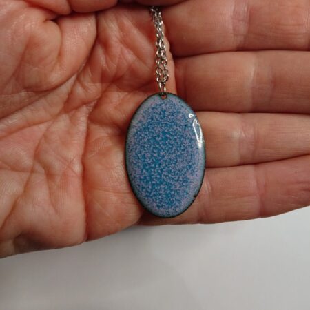 Oval enamelled copper necklace pendant on a silver coloured chain. The necklace is a mix of pink and blue/turquoise. This photo shows the back