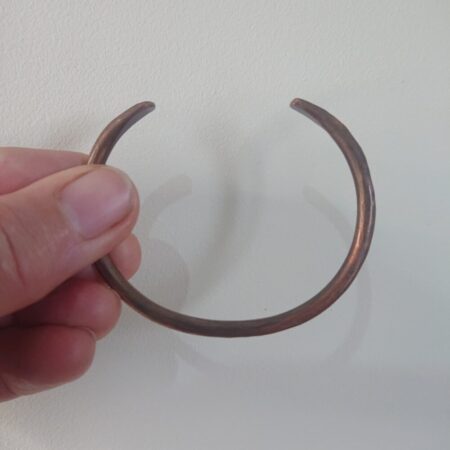Copper wire cuff style bangle or bracelet in aged colour copper with light hammer marks. The bangle has a mid brown aged copper patina, milk chocolate colour or closer to dark chocolate.