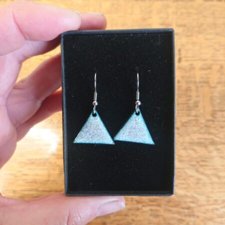Triangle or triangular shaped earrings with ear hooks. The earrings have pale backgrounds with lots of tiny coloured dots or spots. They are shown in their black presentation box.
