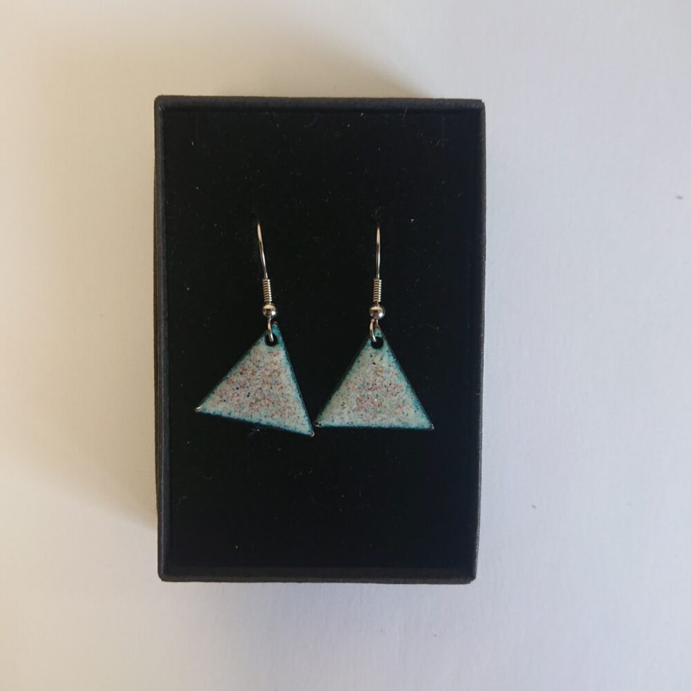 Triangle or triangular shaped earrings with ear hooks. The earrings have pale backgrounds with lots of tiny coloured dots or spots. They are shown in their black presentation box.