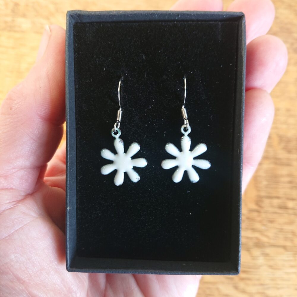 Creamy white enamelled copper earrings with ear hooks and black presentation box. The earrings are flower shaped