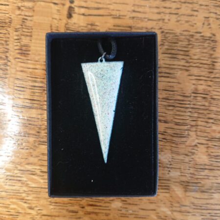 Elongated triangle with the flat at the top necklace. The necklace is enamel on copper in a creamy white with lots of tiny colourful dots or spots in it. The pendant has a black waxed cotton cord and is it a black presentation box