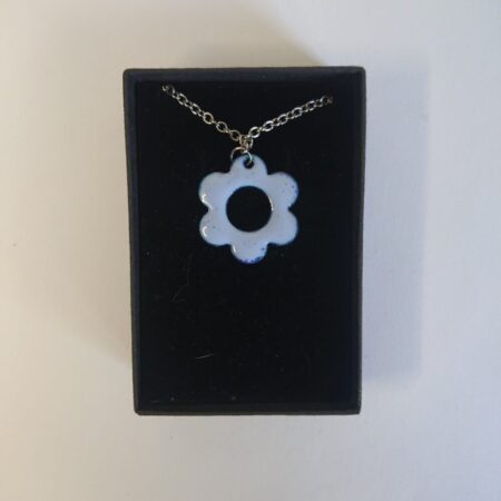 Pale lilac daisy shaped or flower shaped necklace pendant on silver coloured chain. The pendant is enamel on copper and overfired which gives tiny darker dots. This picture shows it in its presentation box.